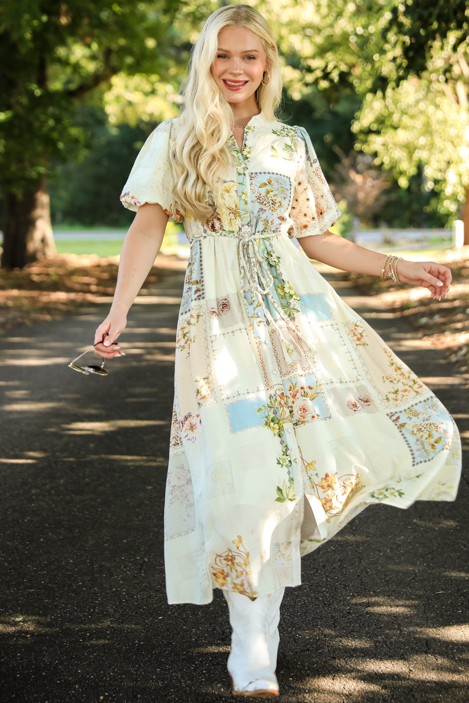 Woman in a floral dress standing outdoors with trees in the background