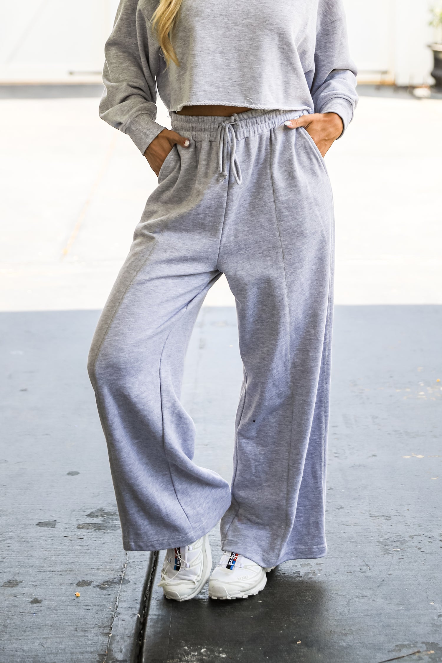 Person wearing a gray sweatshirt and wide-leg pants on a blurred background