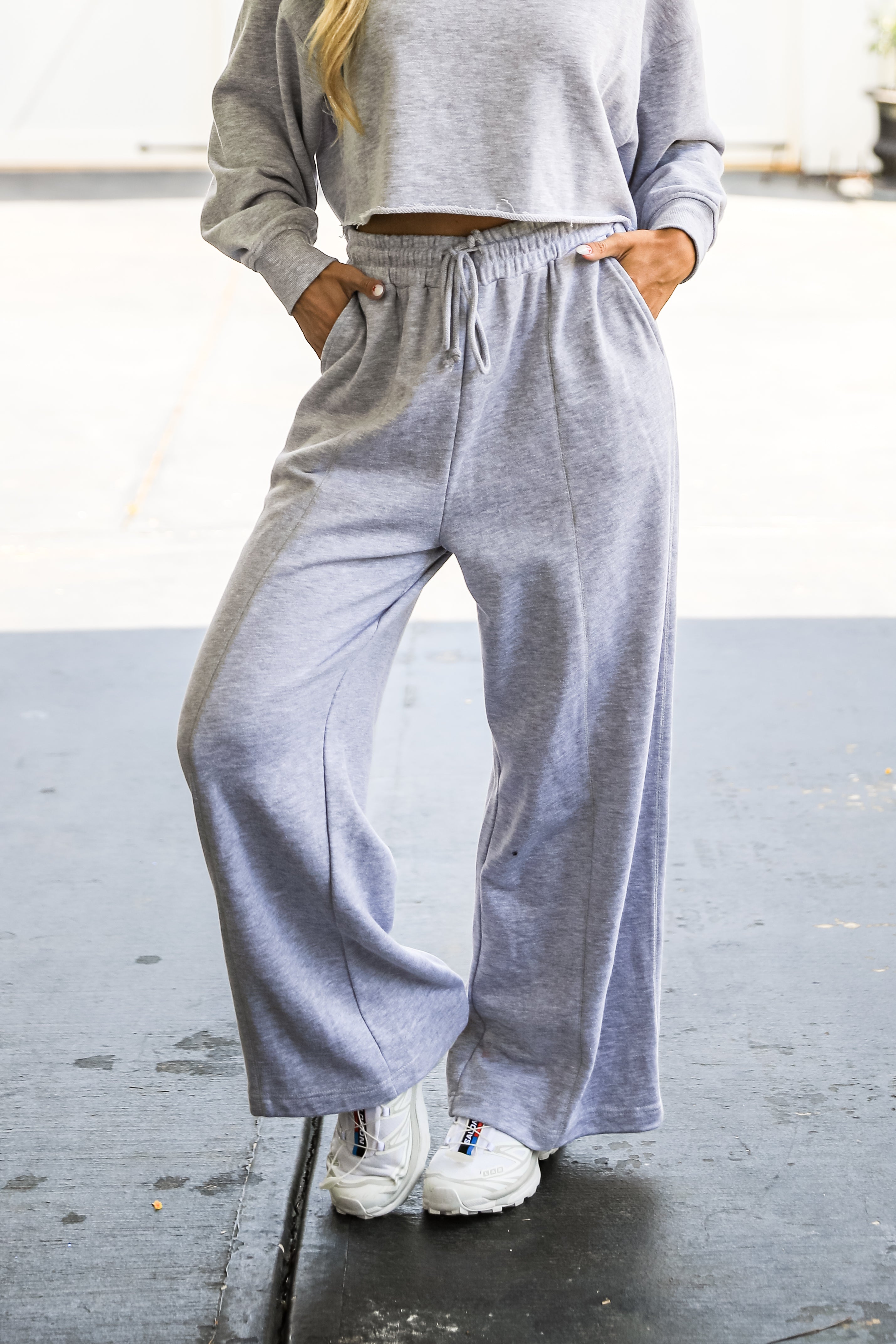 Person wearing a gray sweatshirt and wide-leg pants on a blurred background