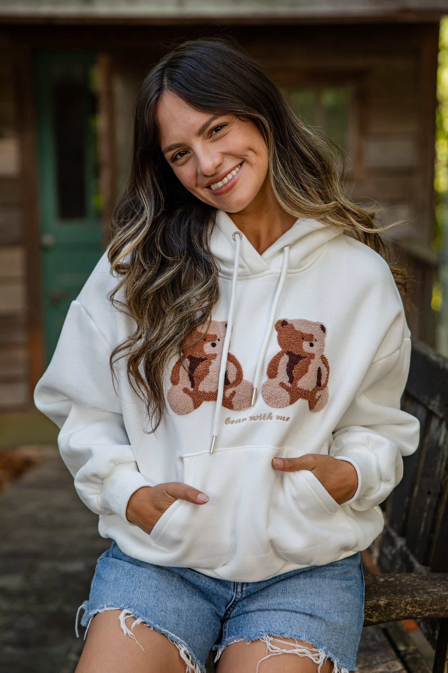 Woman wearing a white hoodie with teddy bear design outdoors