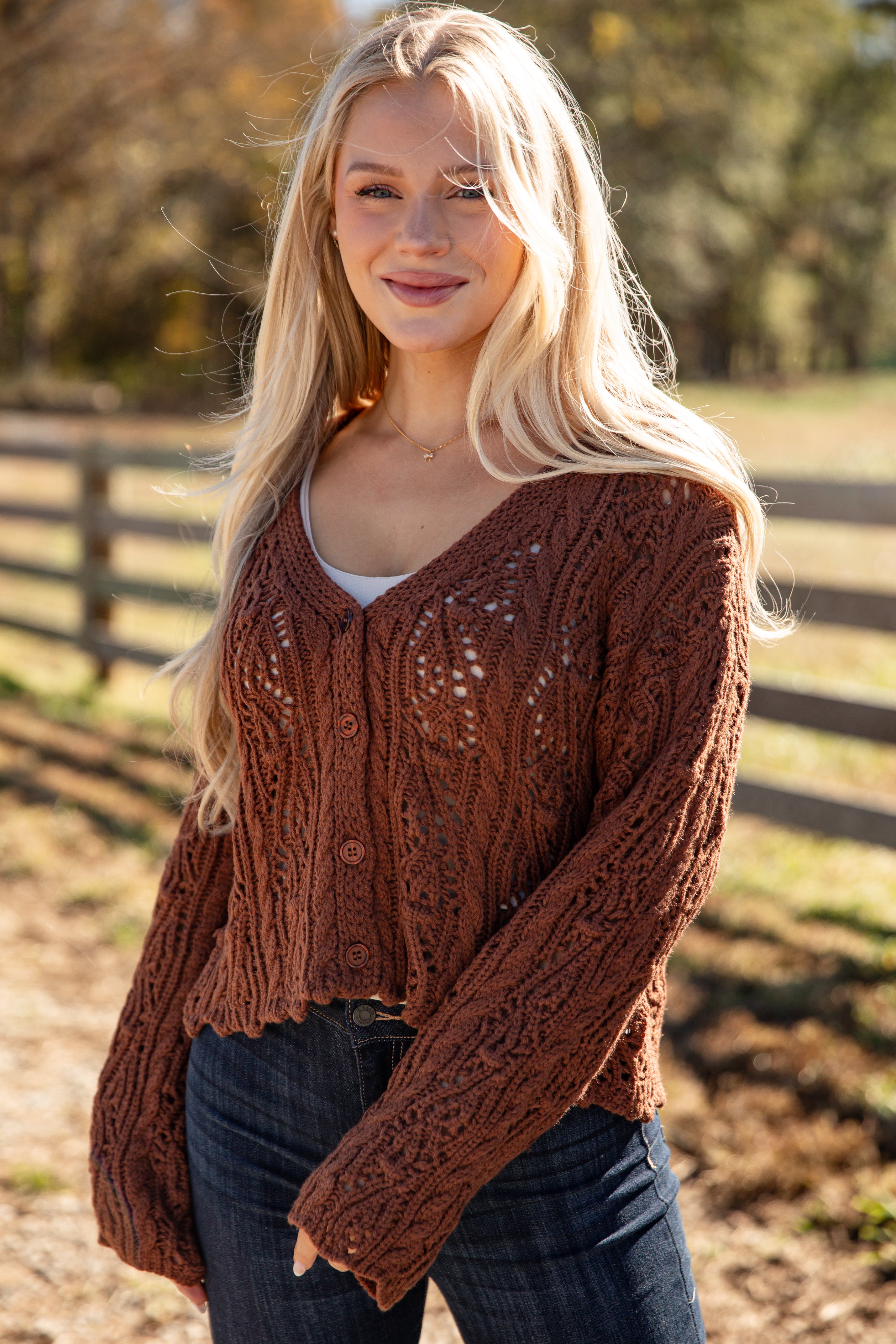 Woman wearing a brown knitted cardigan in an outdoor setting