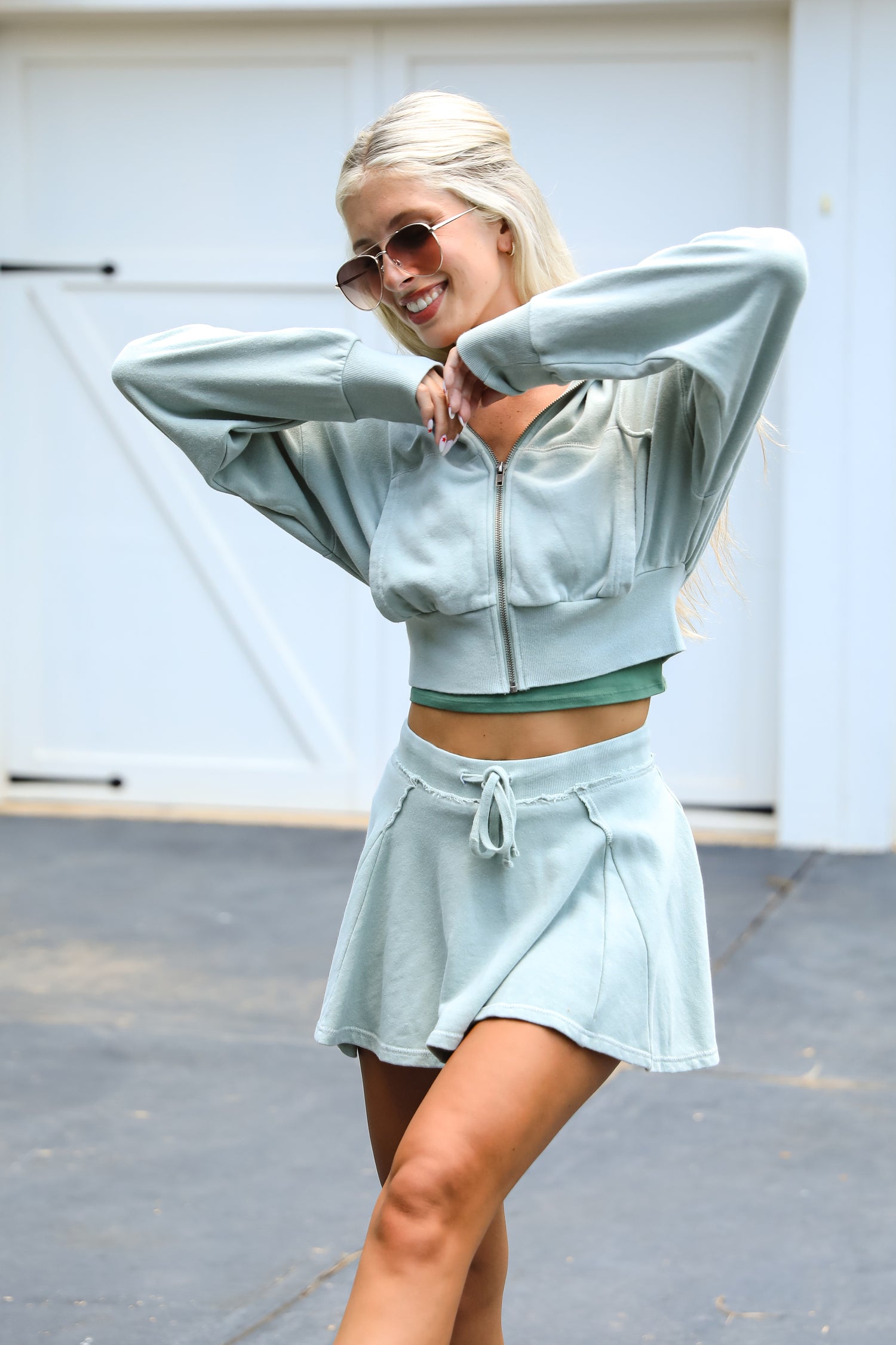 Woman in light blue athletic outfit standing outdoors with a white background