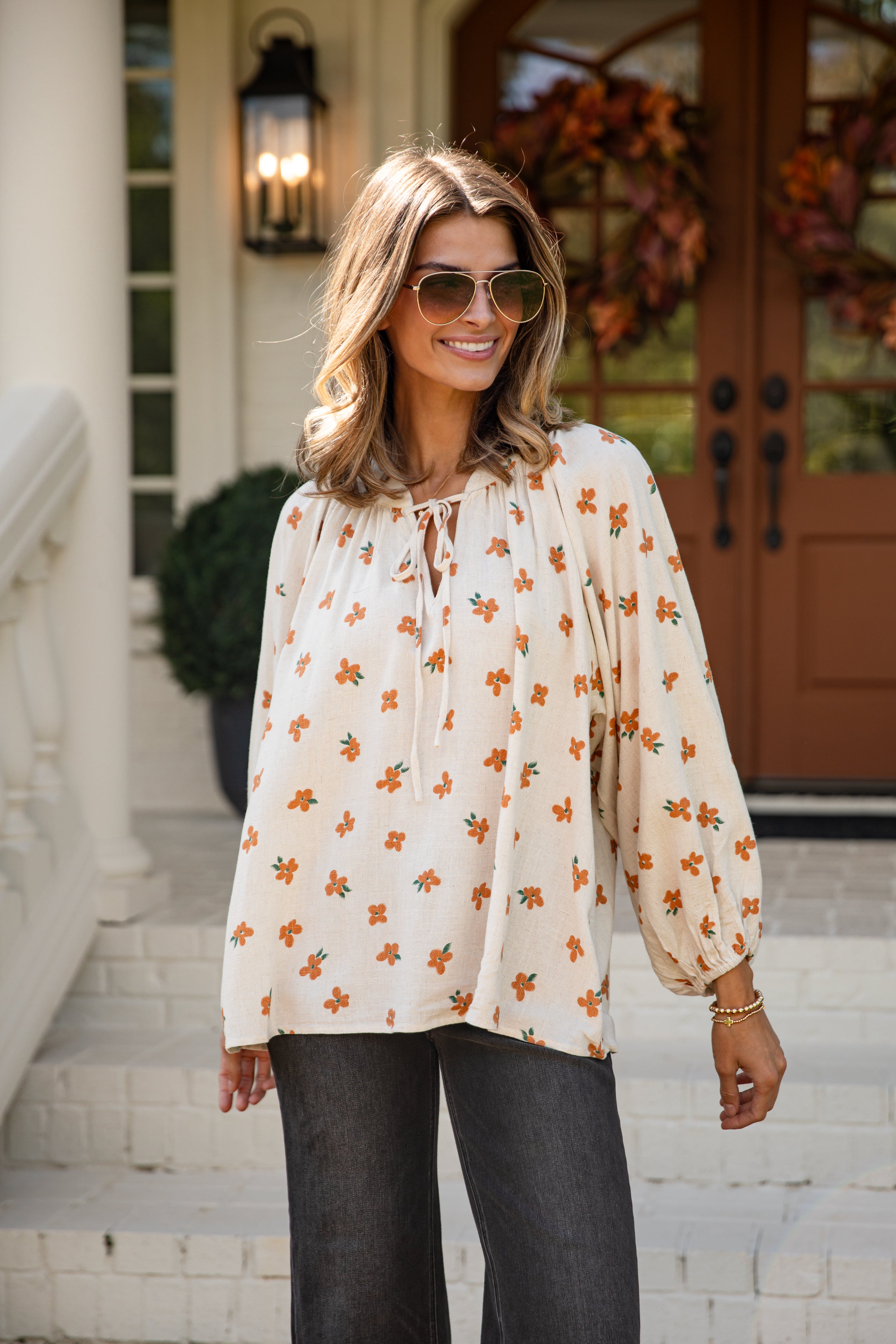 Woman wearing a floral blouse and sunglasses outdoors.