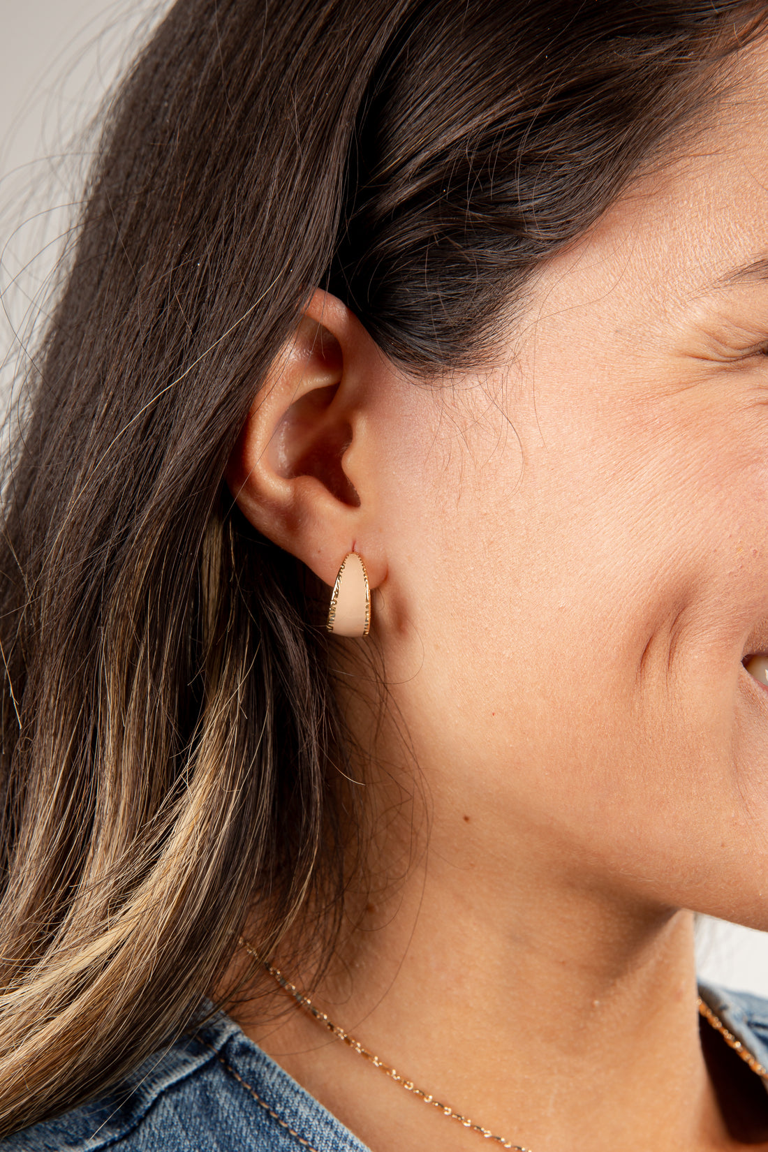 Close-up of a person wearing a small beige earring.