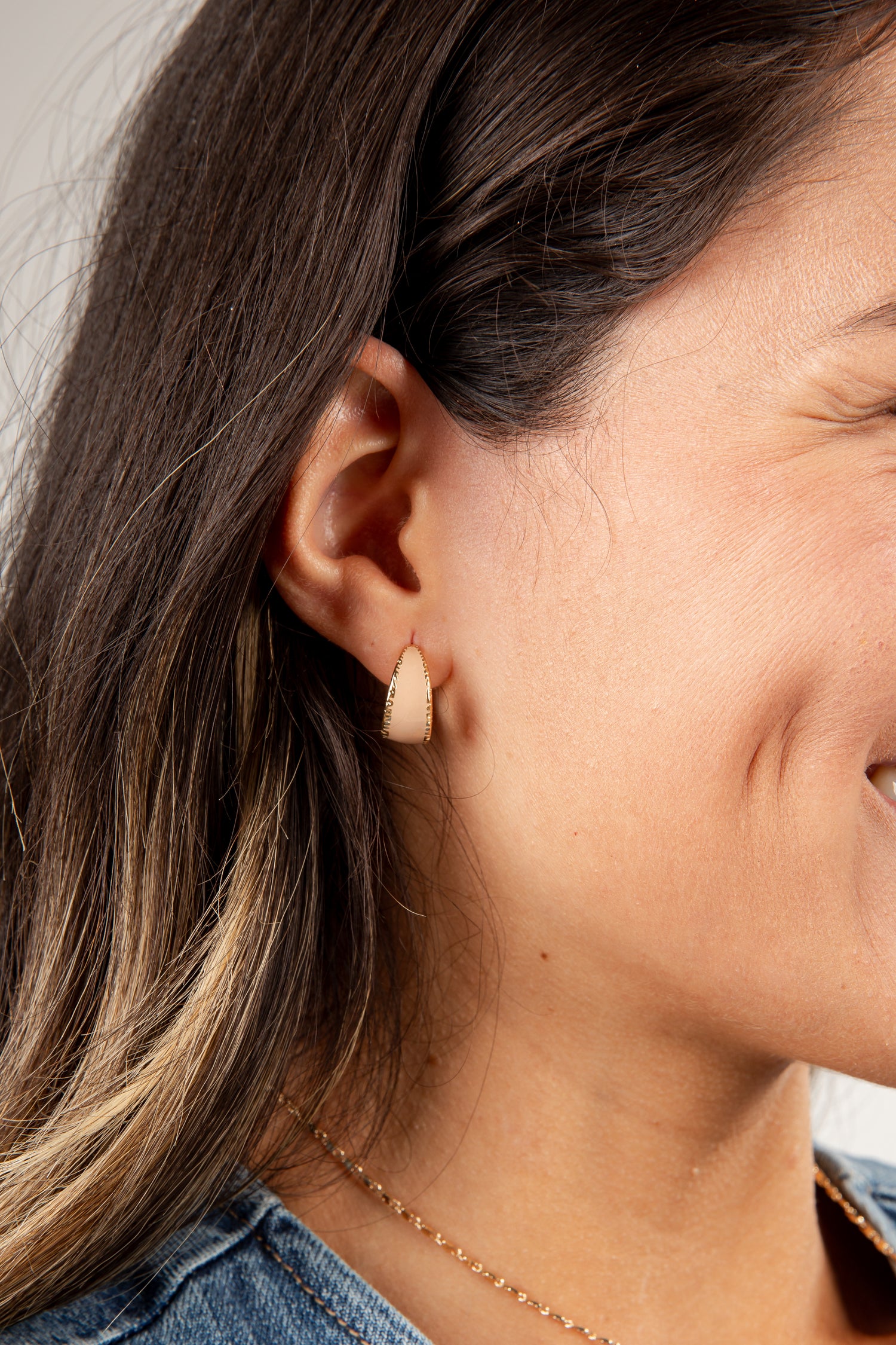 Close-up of a person wearing a small beige earring.
