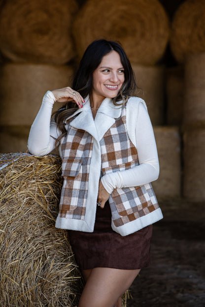 Woman in a plaid vest and white shirt standing in front of hay bales