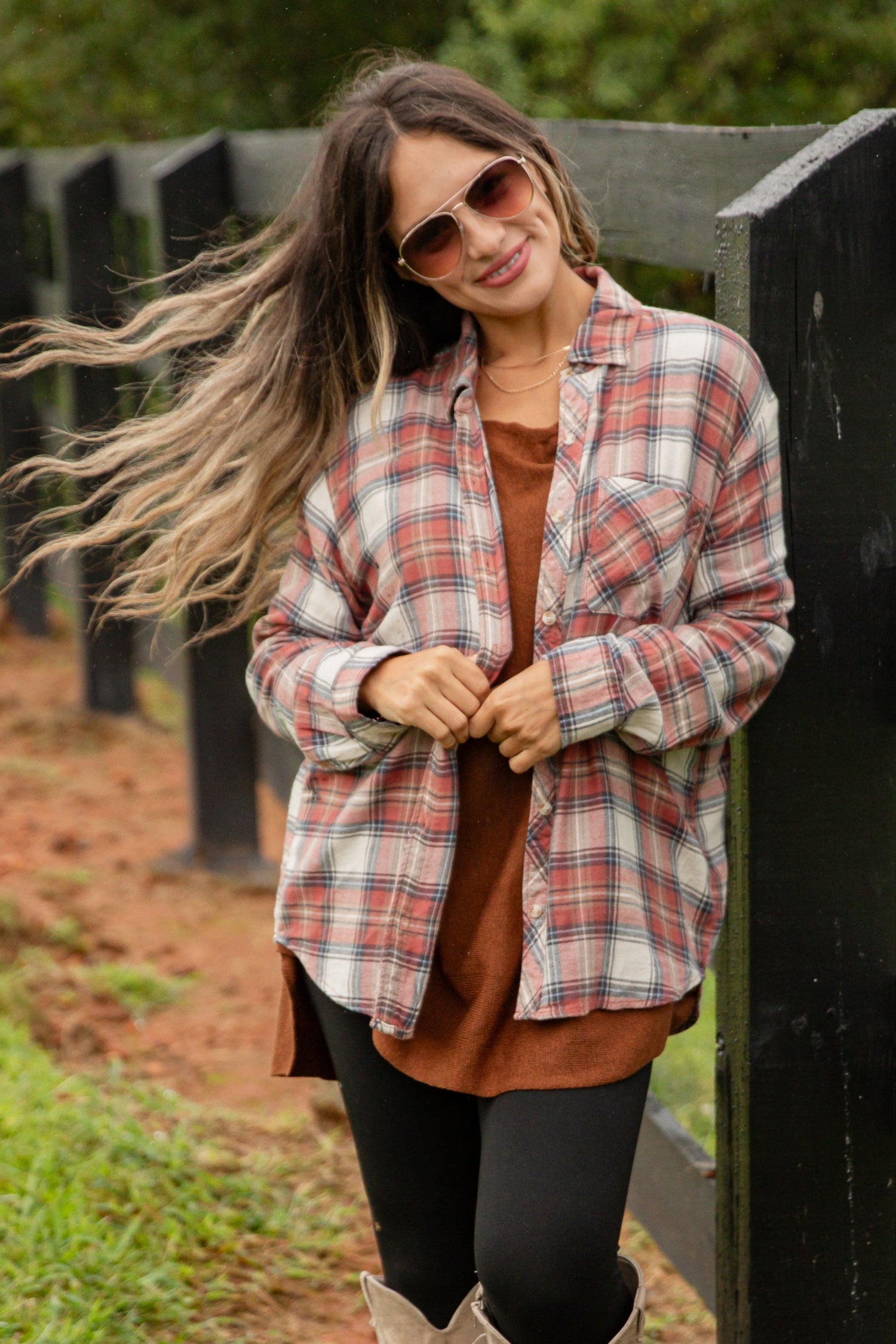 Woman standing by a wooden fence in a rural setting