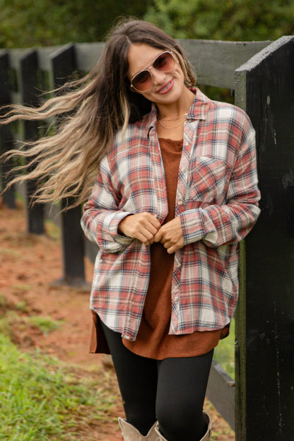 Woman standing by a wooden fence in a rural setting