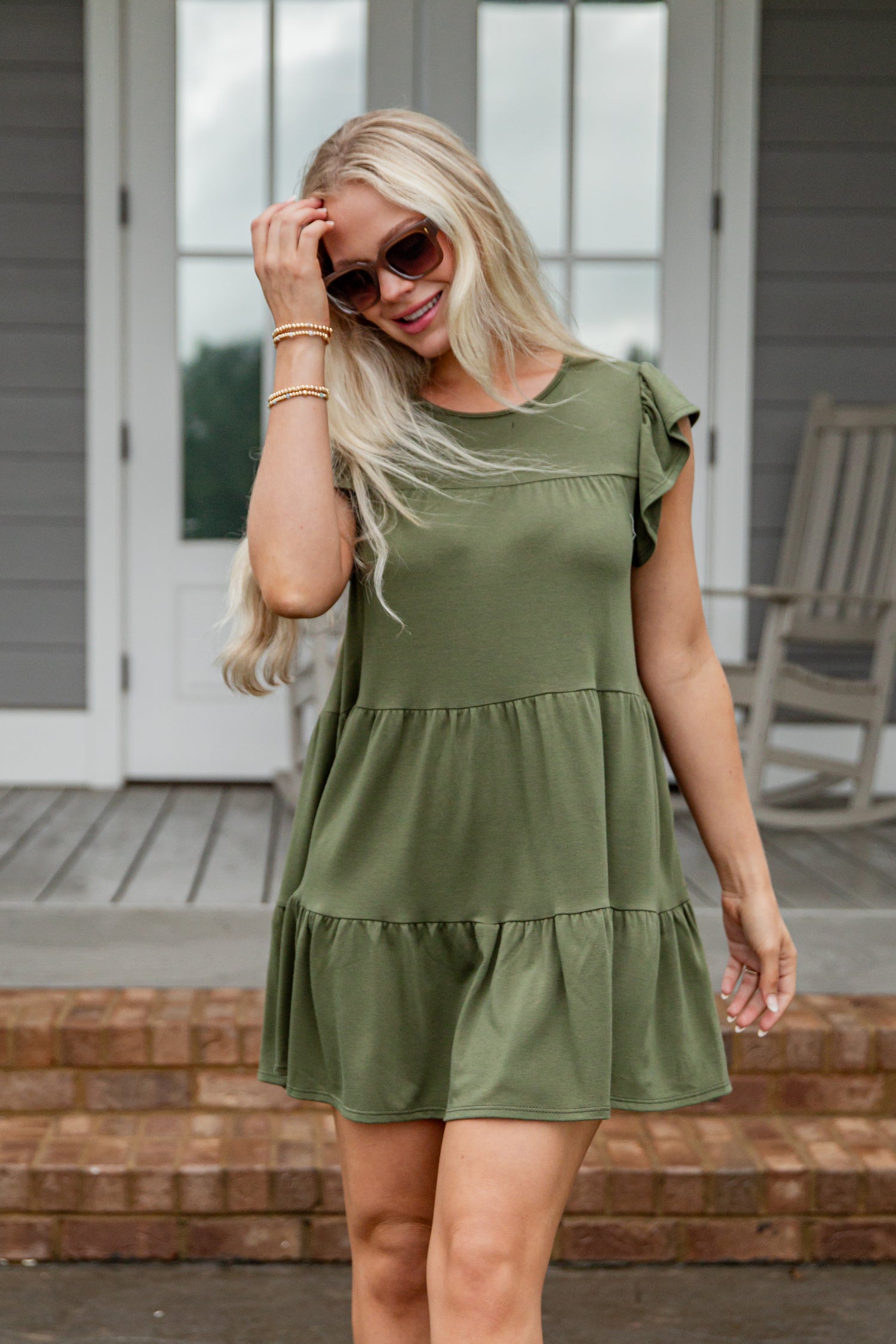 Woman wearing an olive green dress on a porch