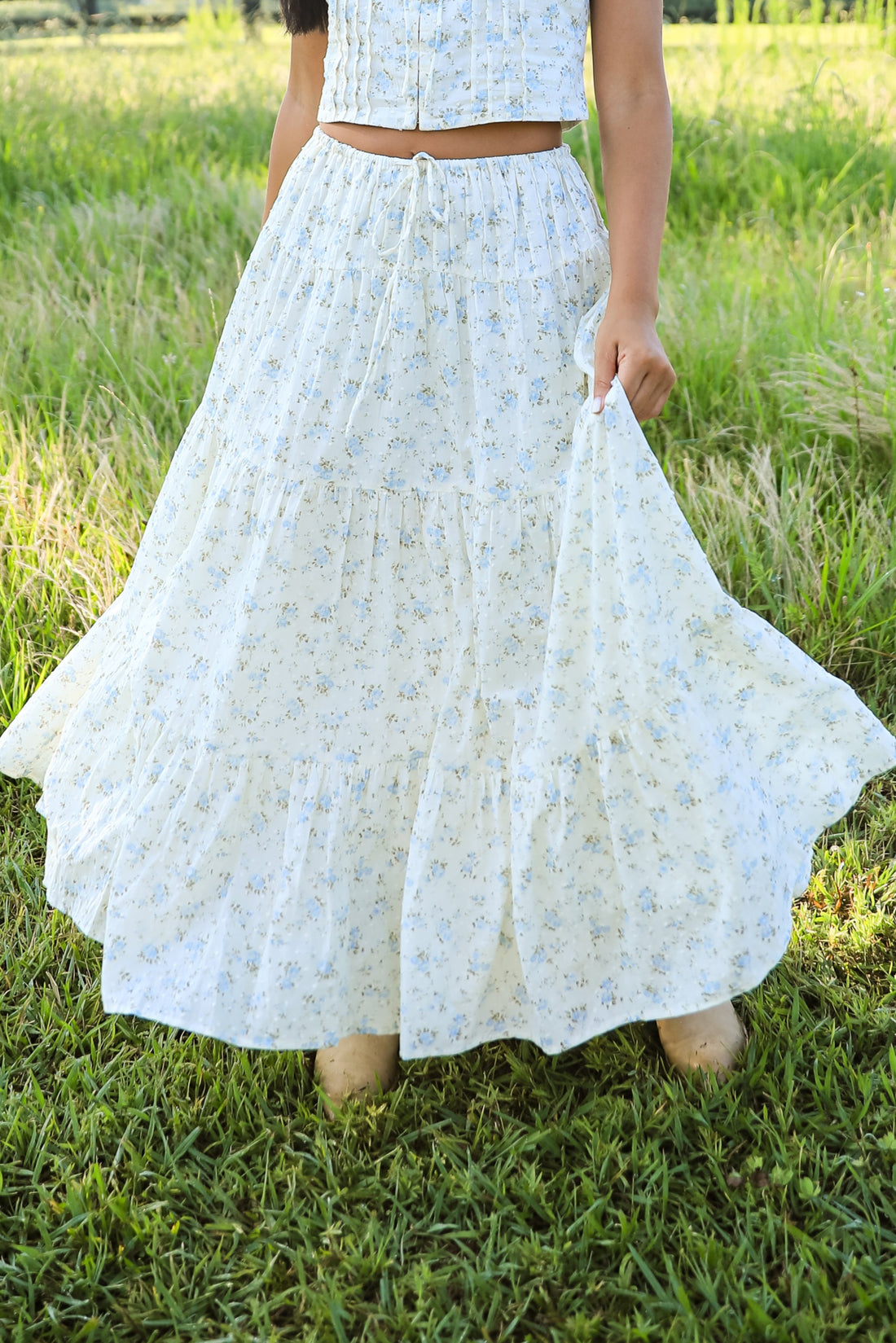 Woman in a white lace outfit standing in a grassy field