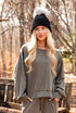 Woman wearing a black beanie and gray sweatshirt in a forest setting