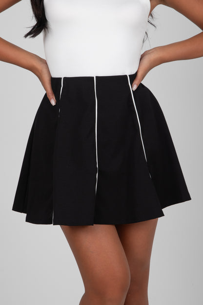 Person wearing a black skirt with white trim on a gray background