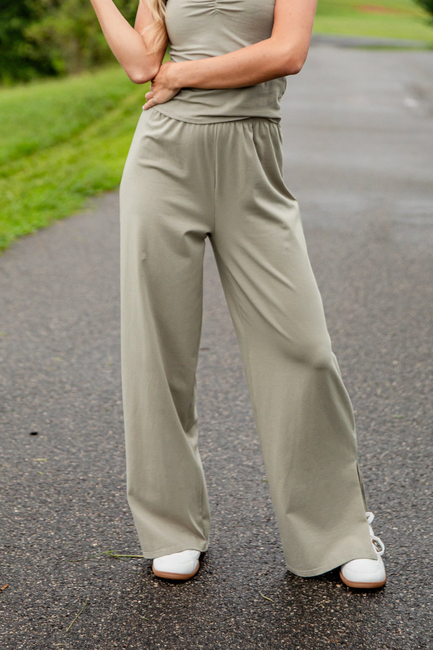 Person wearing a light green outfit with wide-leg pants on a road.