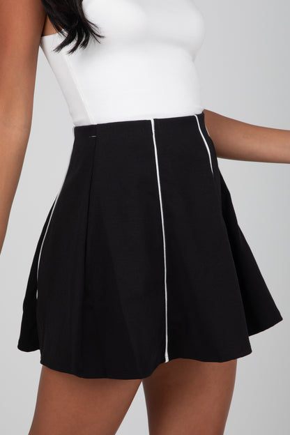 Black skirt with white trim worn by a person on a plain background