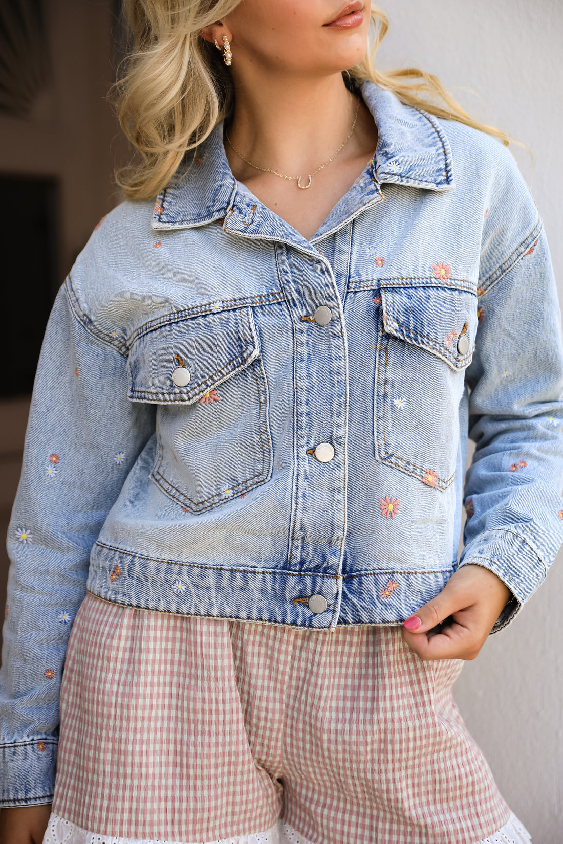 Person wearing a light blue denim jacket with floral embroidery.
