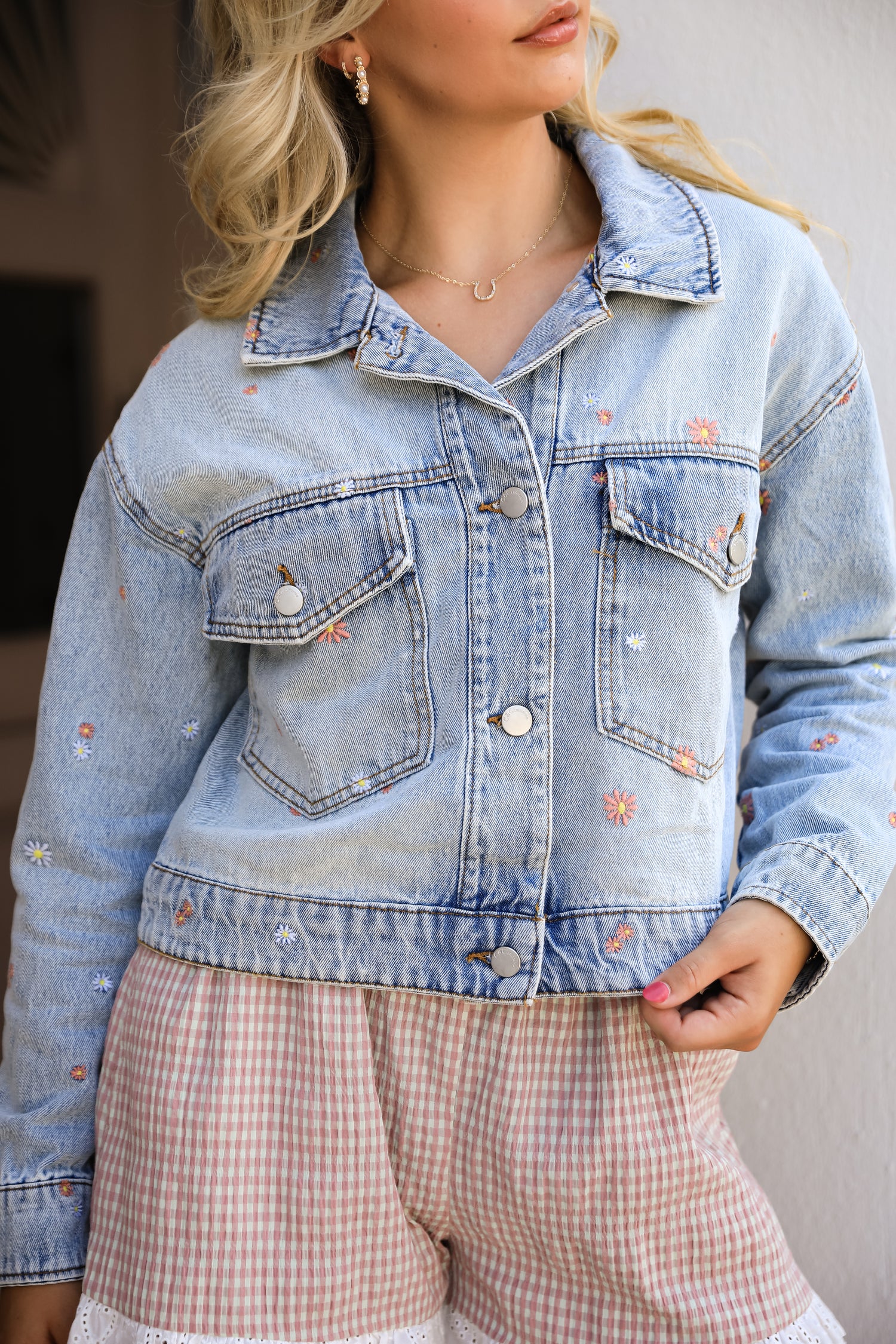 Person wearing a light blue denim jacket with floral embroidery.