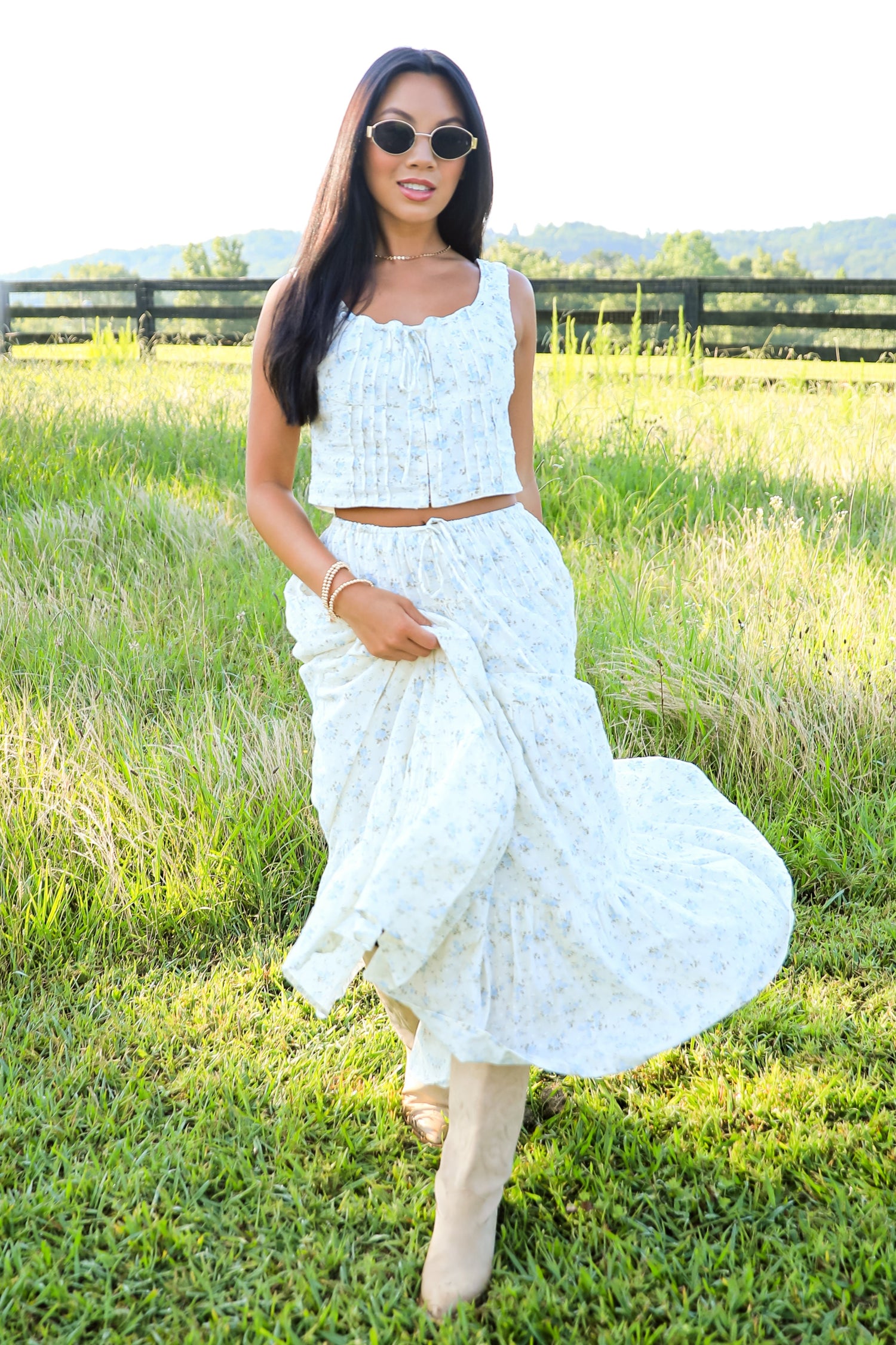 Woman in a white dress standing in a grassy field with mountains in the background