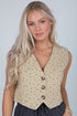 Woman wearing a beige floral vest against a plain background