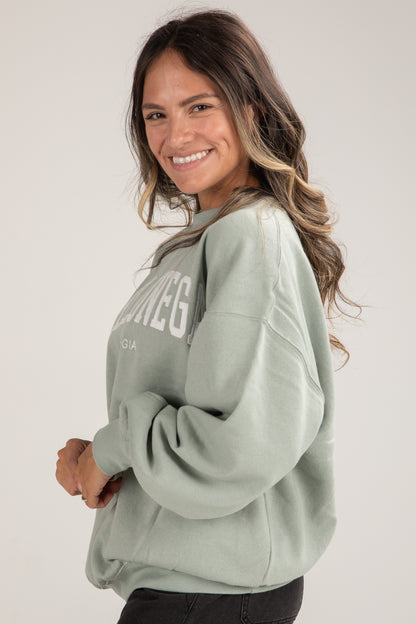 Woman wearing a light green sweatshirt with text on a plain background