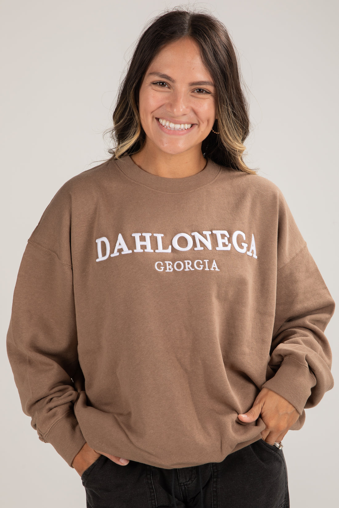 Person wearing a brown sweatshirt with &