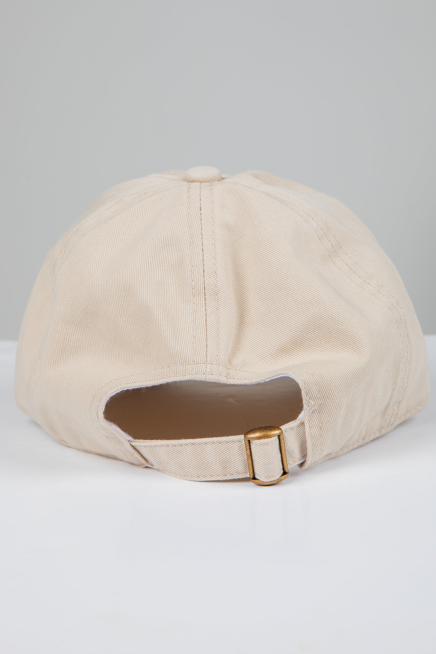 Beige baseball cap with a brown patch on a light gray background