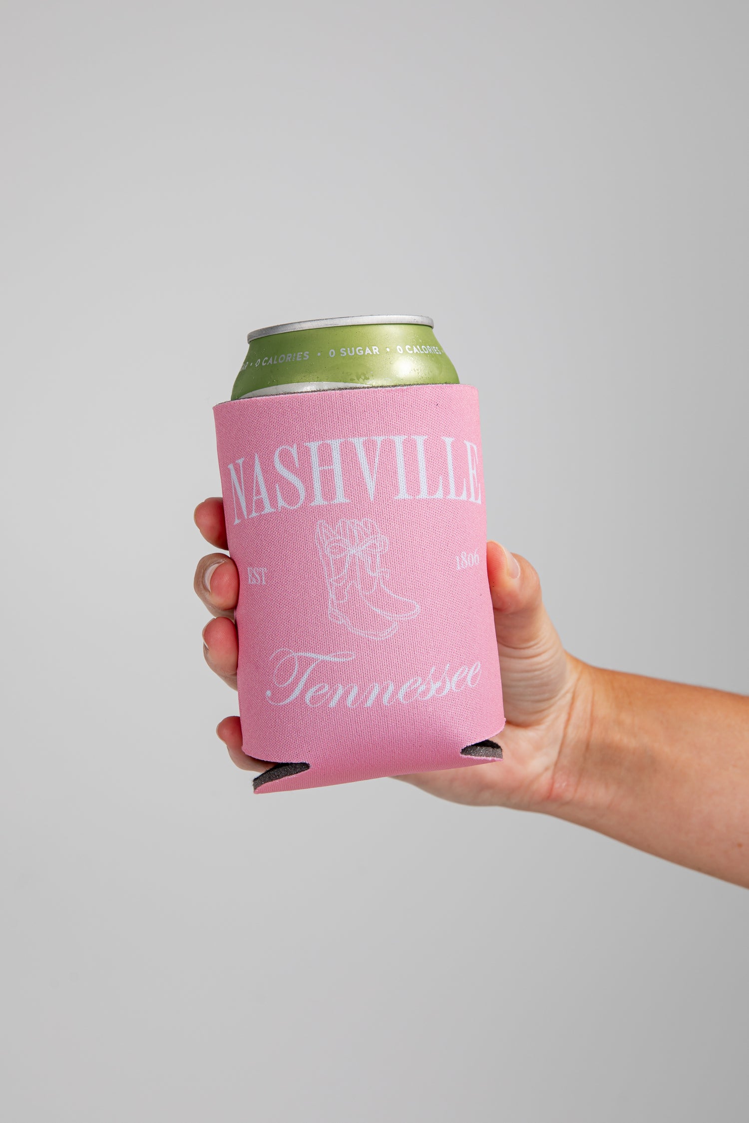 Hand holding a can with a pink sleeve featuring &