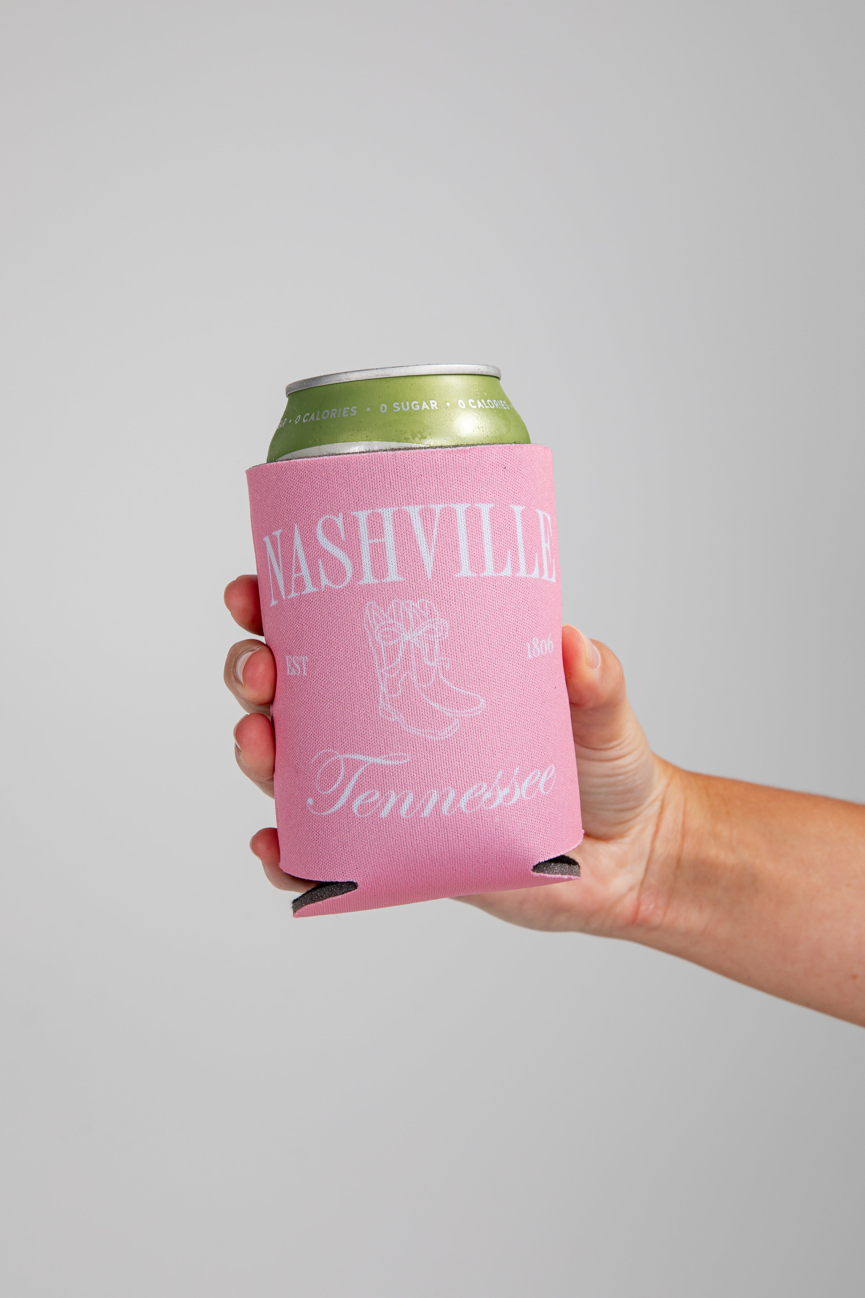 Hand holding a can with a pink sleeve featuring &