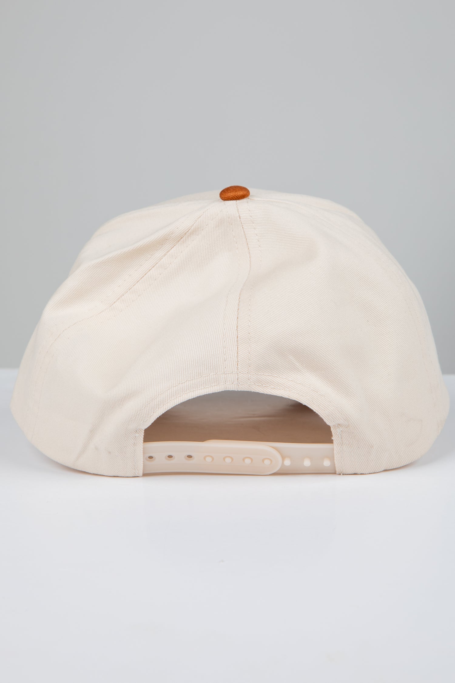 Beige cap with a brown button on a light gray background