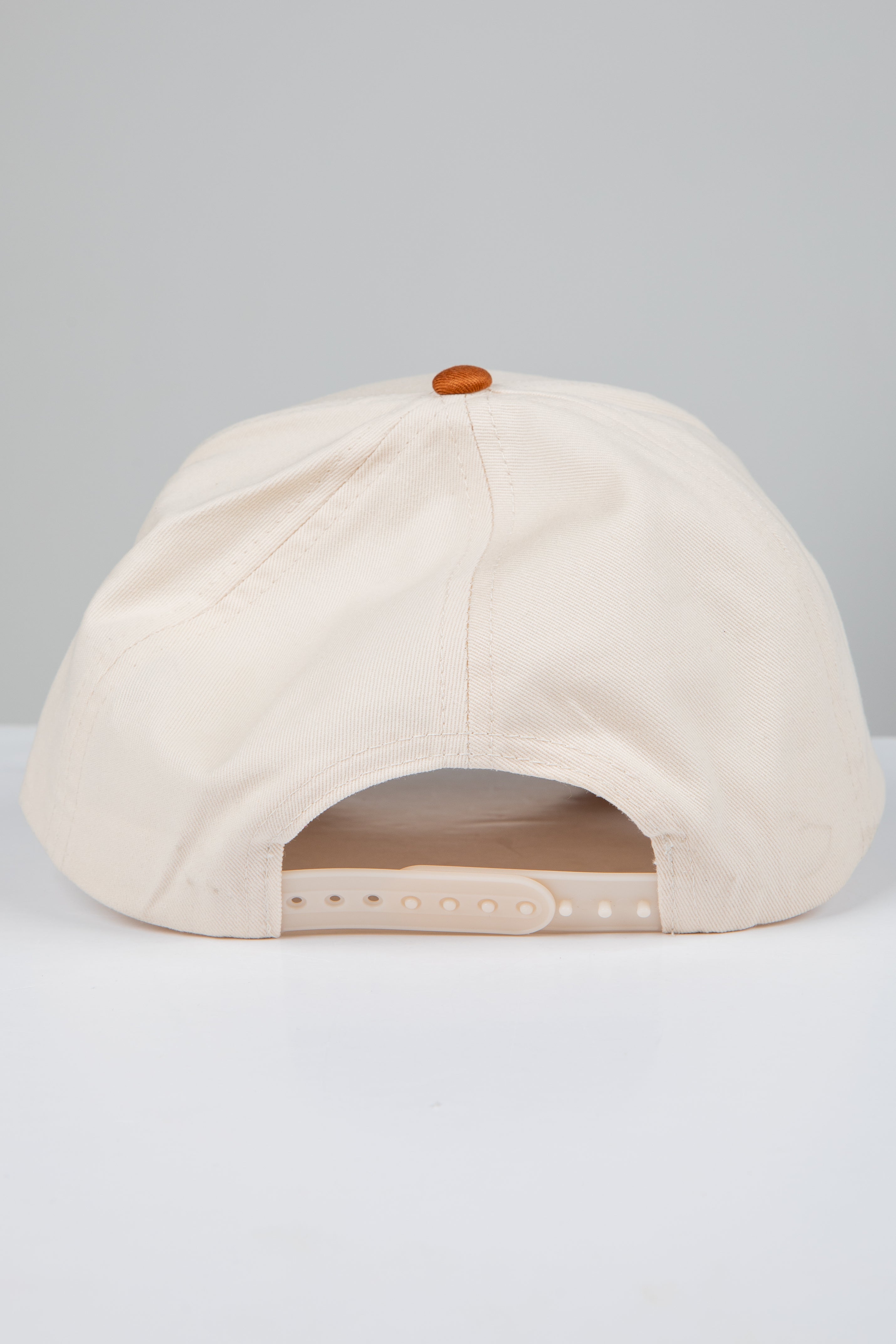 Beige cap with a brown button on a light gray background