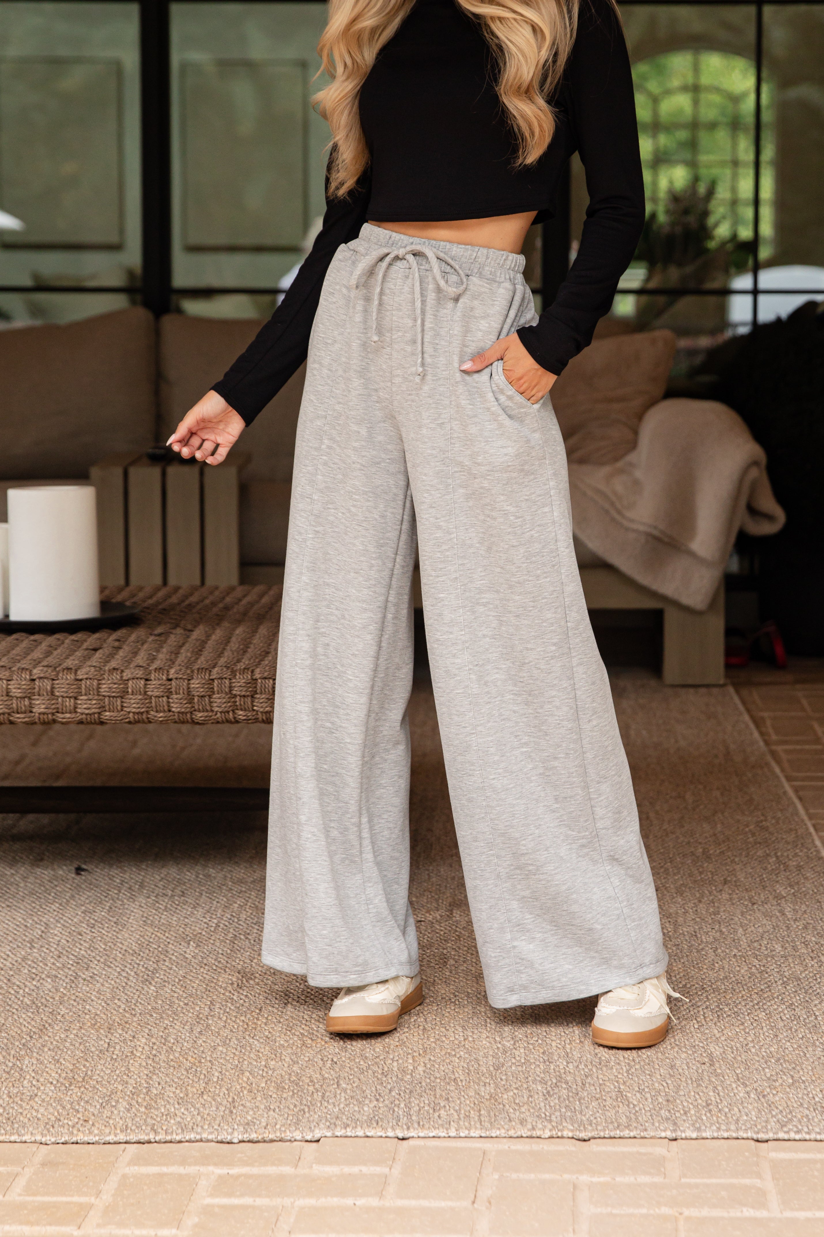 Person wearing gray wide-leg pants and a black long-sleeve top in an indoor setting.
