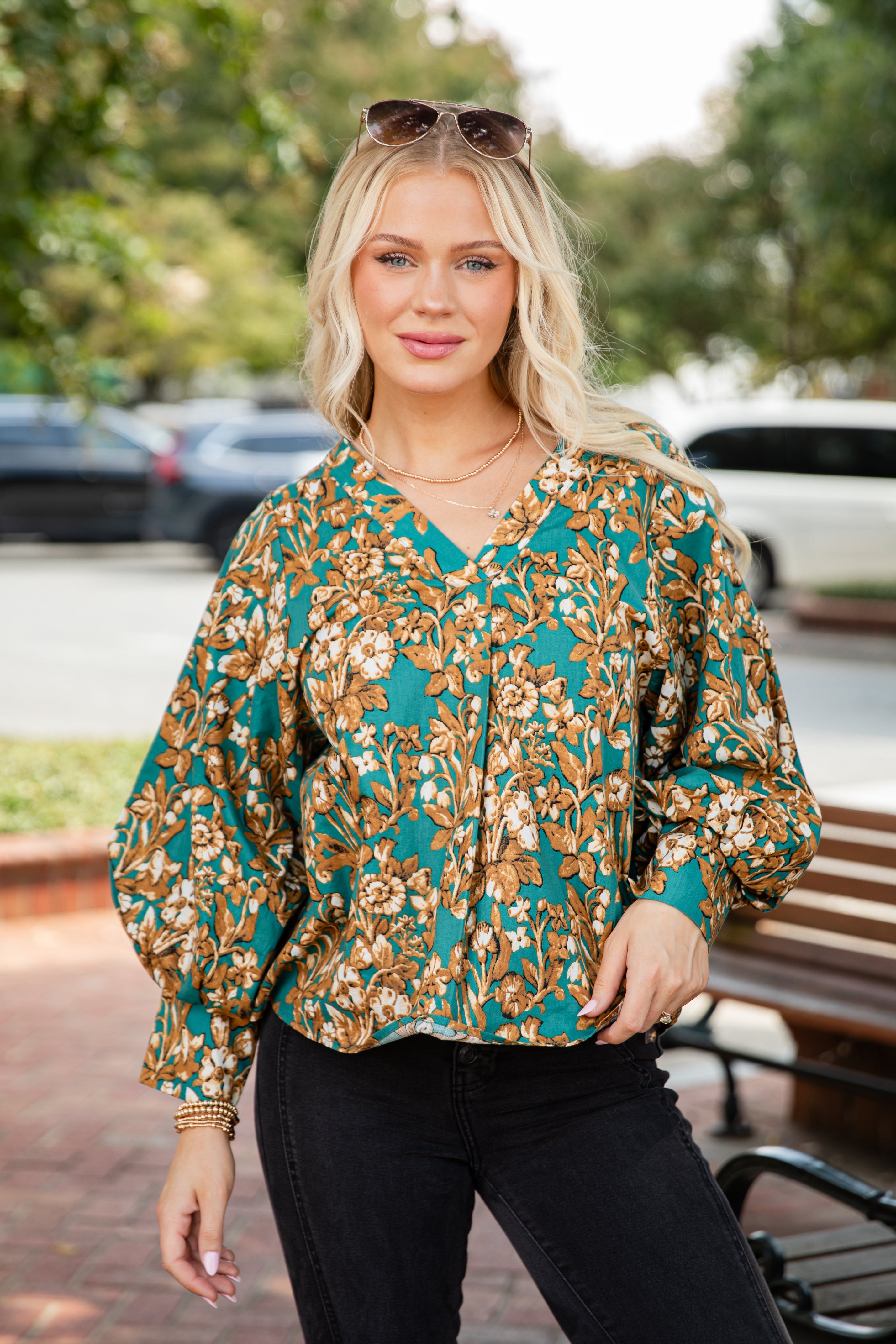 Woman wearing a floral blouse with a blurred outdoor background