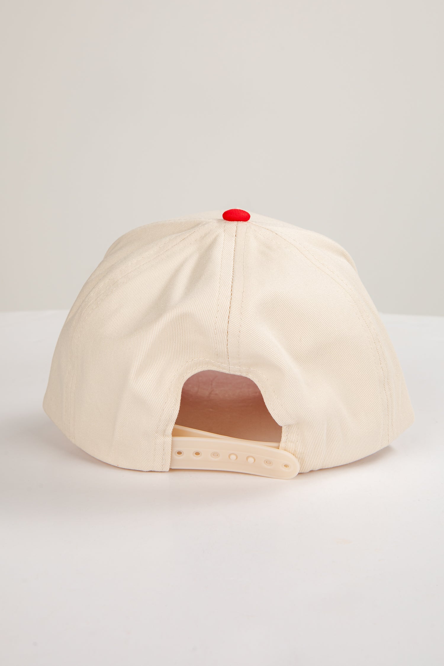 Beige cap with a red button on a light gray background