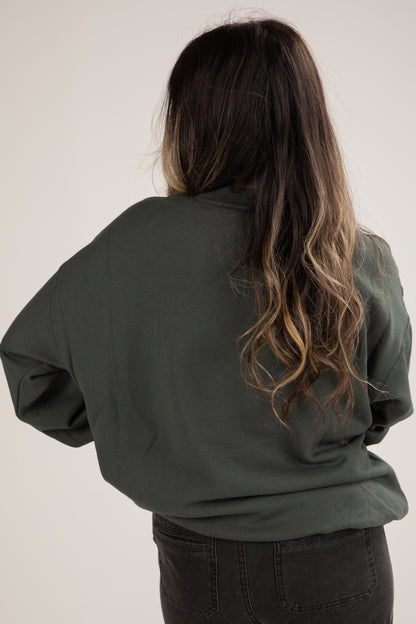 Person wearing a green jacket with long, wavy hair on a plain background