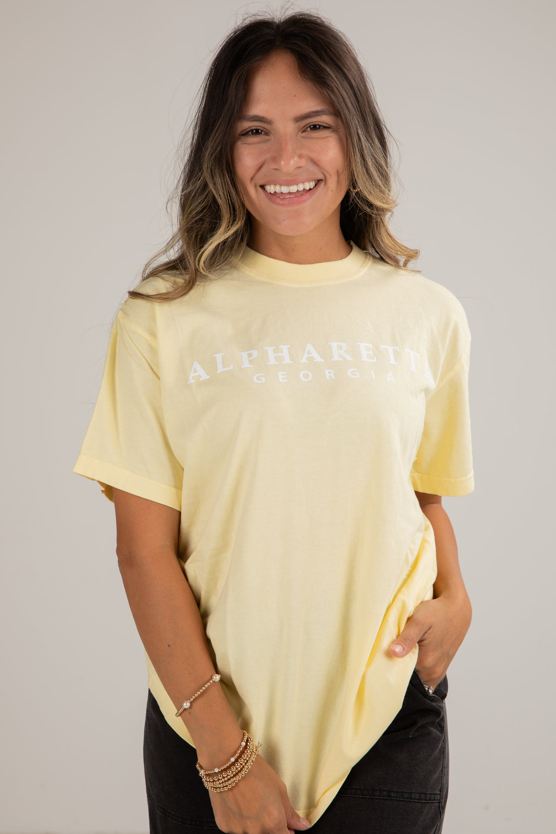 Woman wearing a light yellow t-shirt with text on a plain background