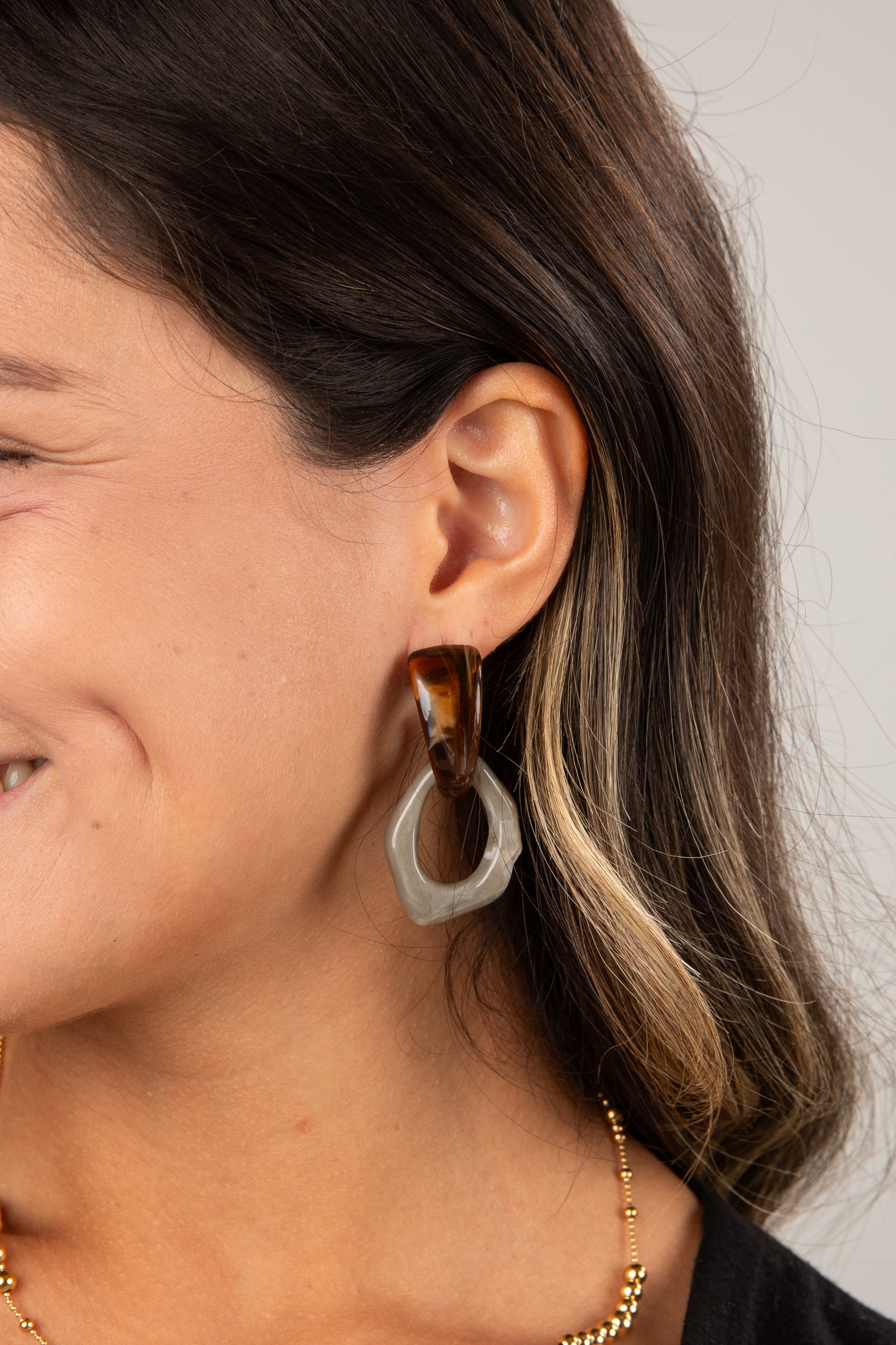 Close-up of a person wearing a tortoiseshell hoop earring with a white circular accent.