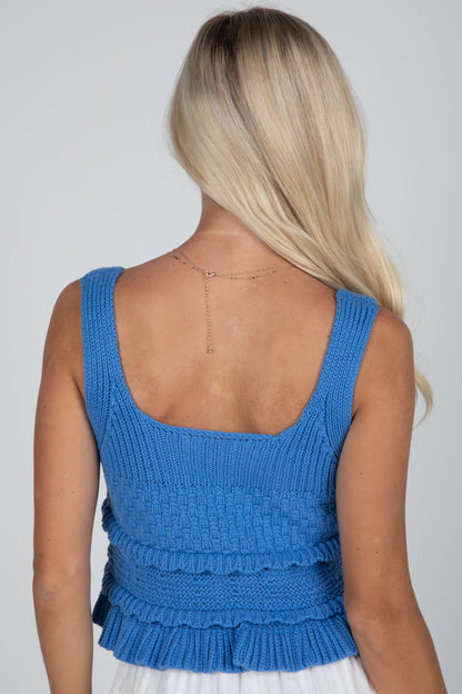 Blue knitted top worn by a person on a plain background