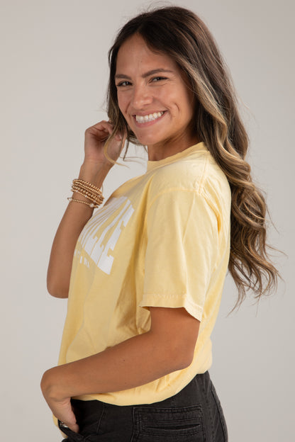 Woman wearing a yellow t-shirt with text on a plain background