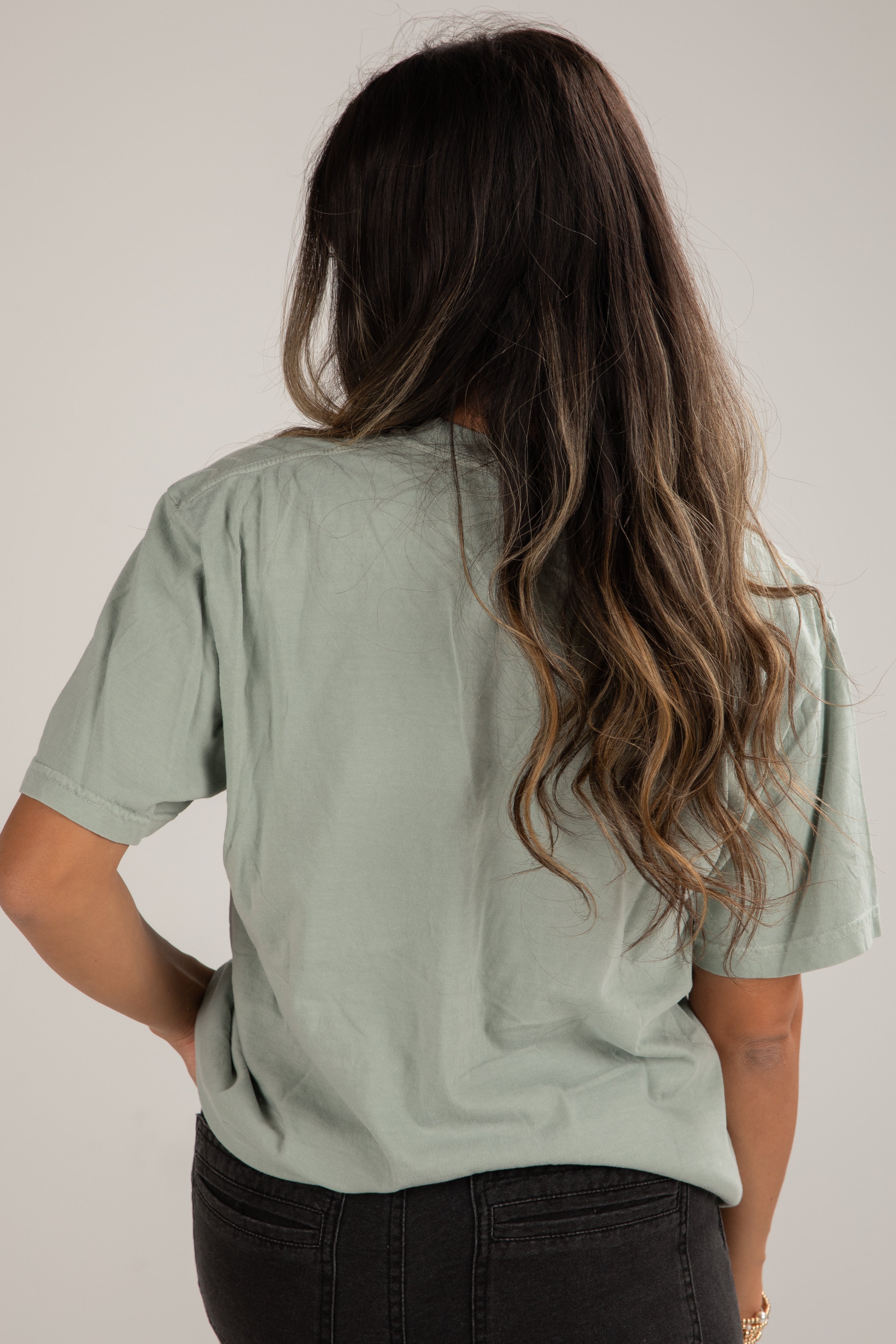 Person wearing a light green t-shirt against a plain background