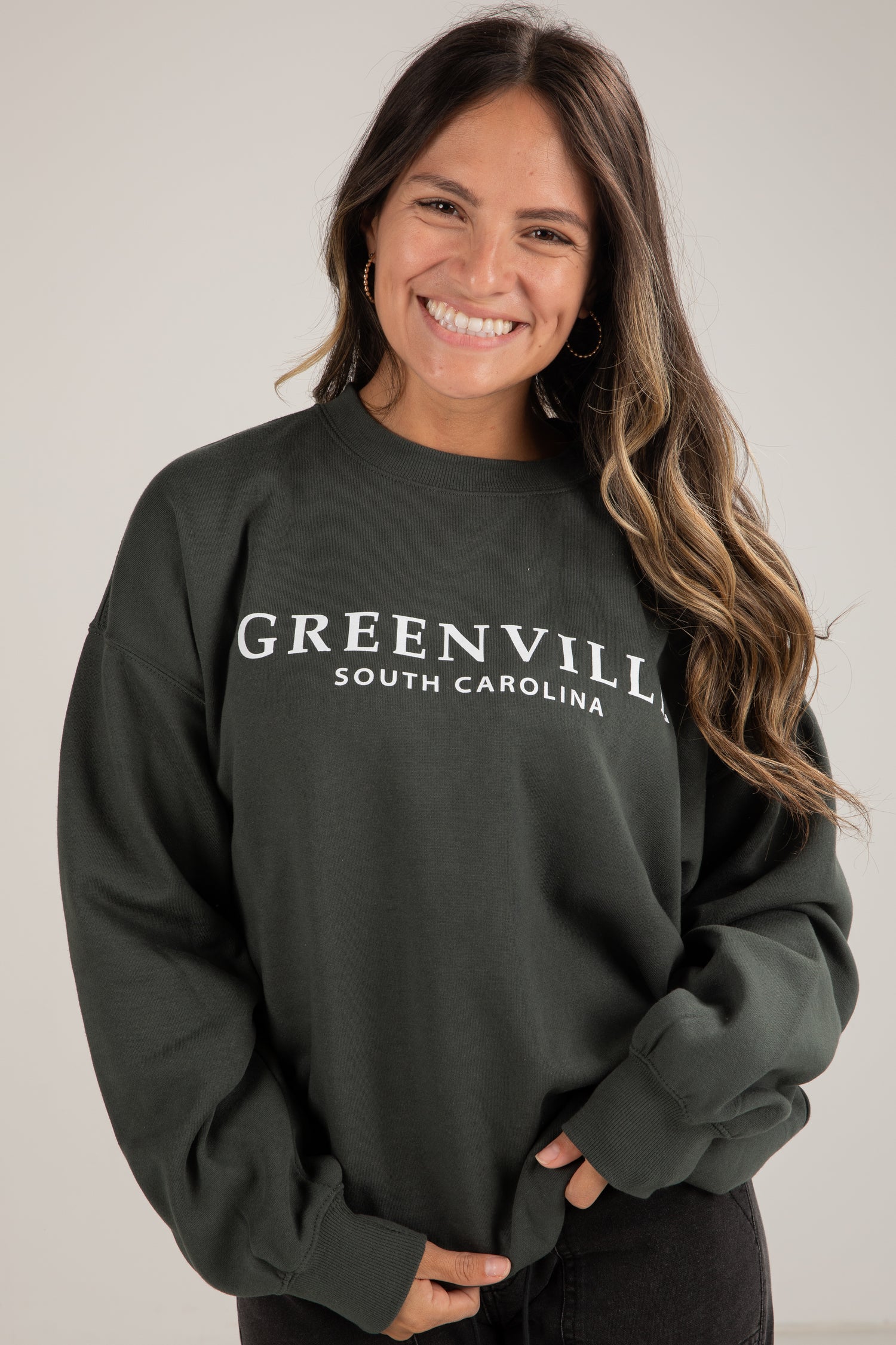 Woman wearing a dark green sweatshirt with &