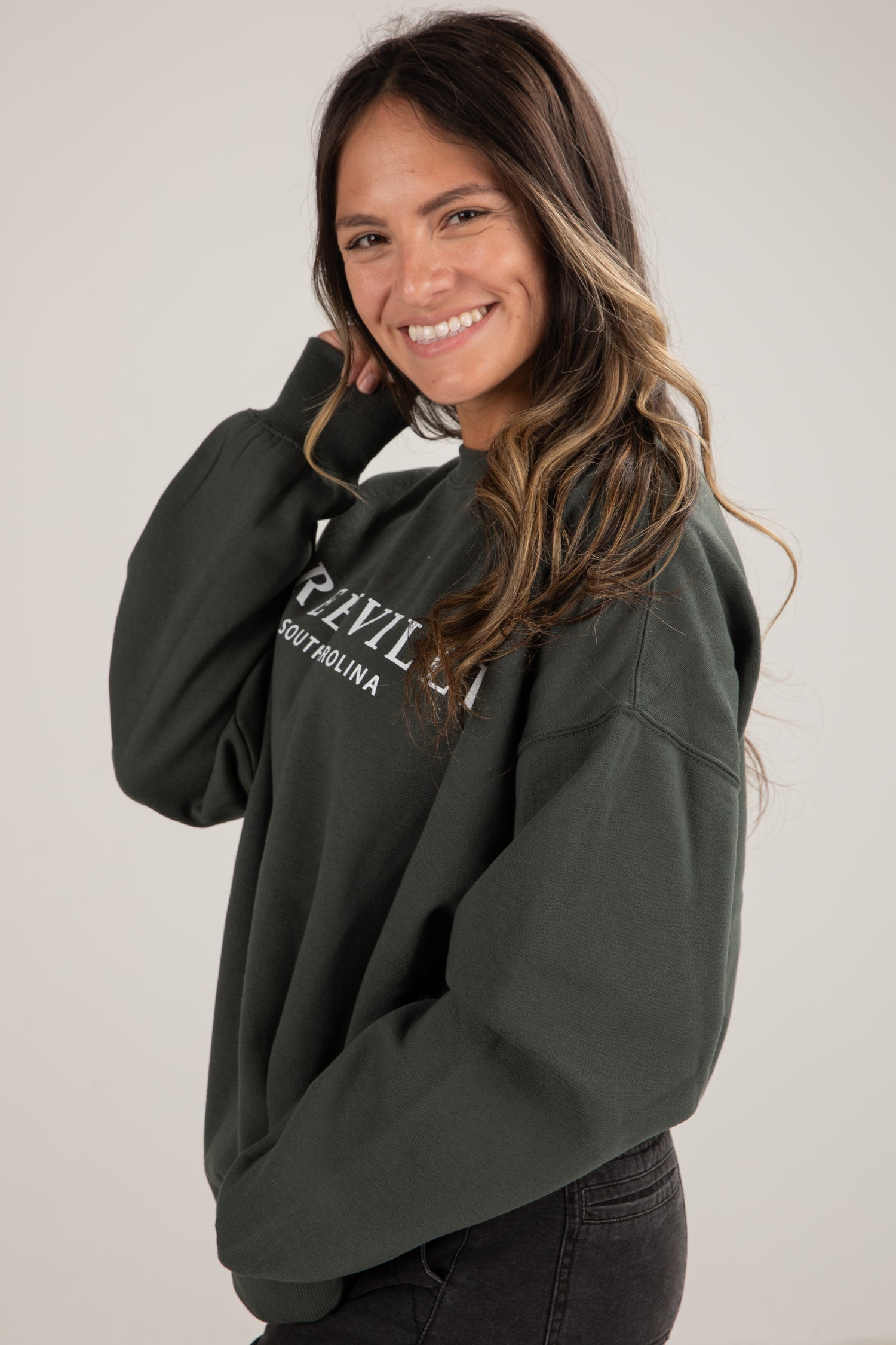 Woman wearing a dark green hoodie with text on a plain background