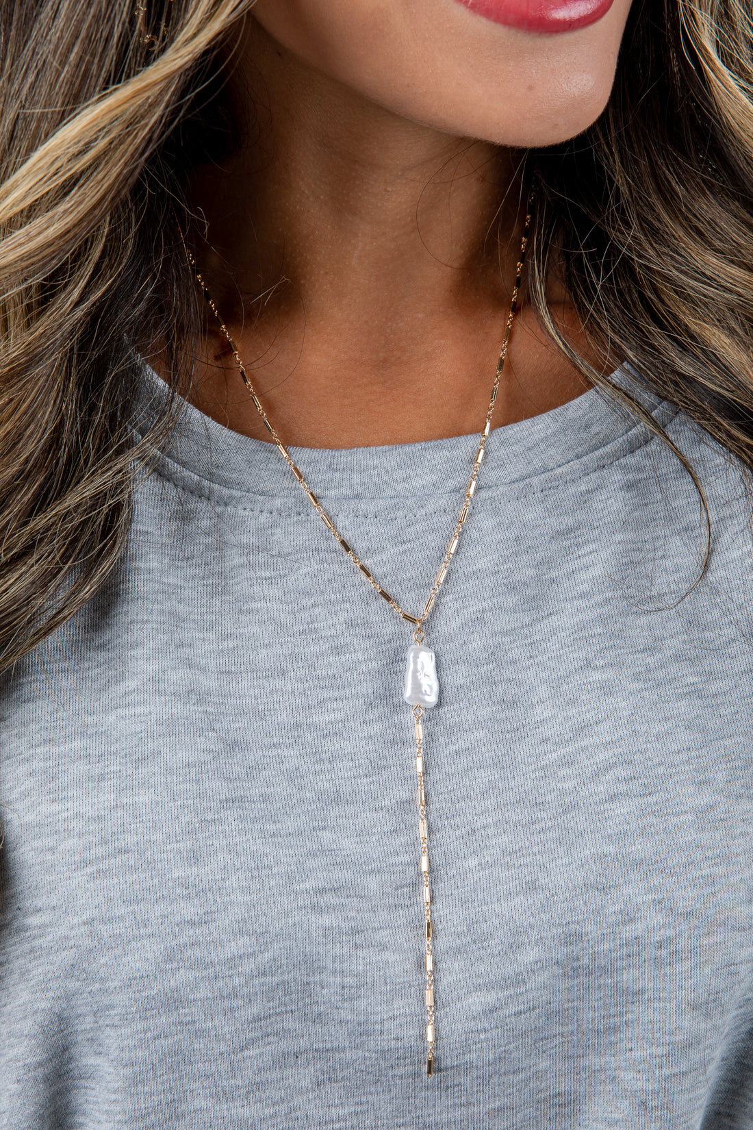 Necklace with a pendant worn by a person against a neutral background