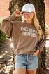 A woman wearing a brown sweatshirt with the text &