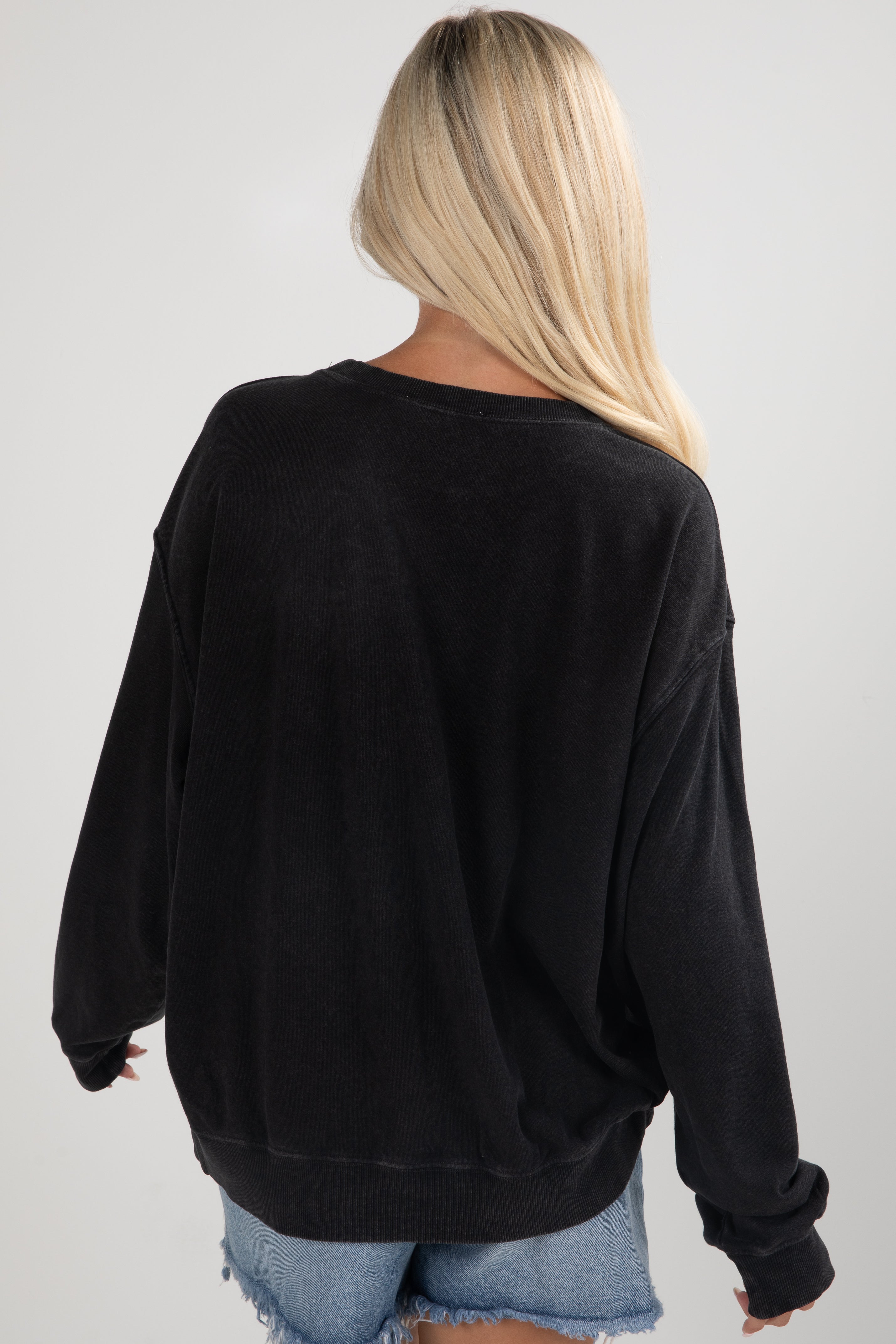 Person wearing a black oversized sweatshirt on a plain background