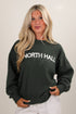 Woman wearing a dark green sweatshirt with &