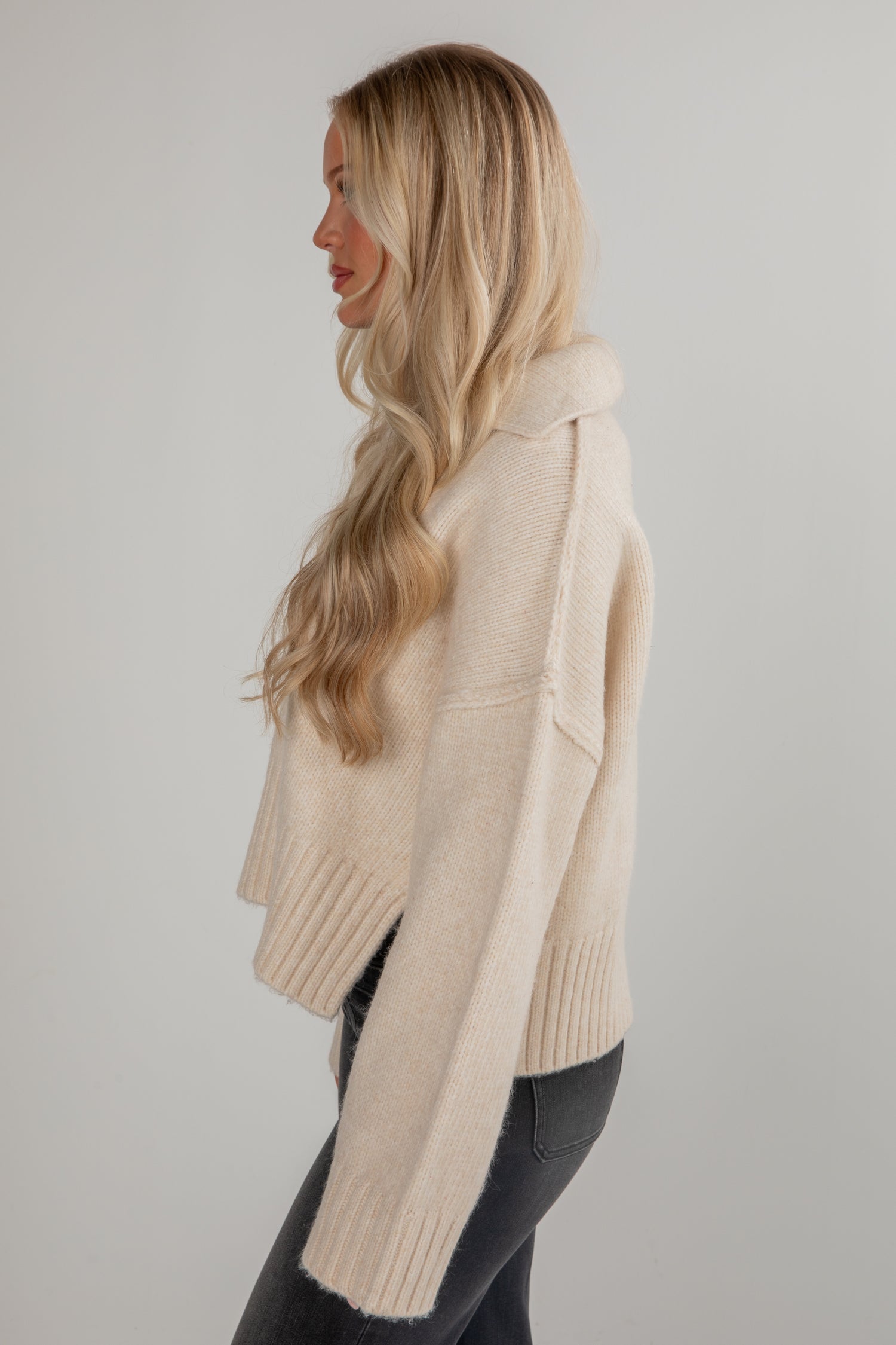 Woman wearing a beige sweater against a plain background
