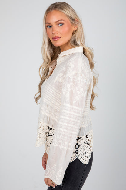 Woman wearing a white lace top against a plain background