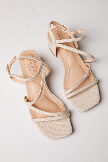 Pair of beige strappy sandals on a light gray background
