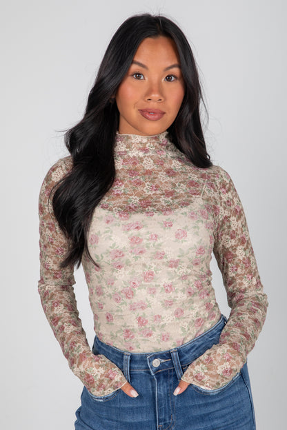 Woman wearing a floral long-sleeve top against a plain background