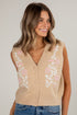 Woman wearing a beige sleeveless cardigan with floral embroidery on a plain background