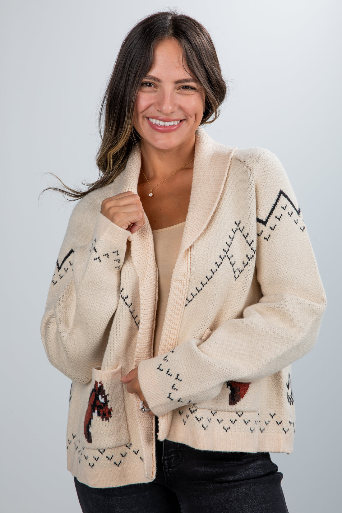 Woman wearing a cream-colored cardigan with patterned design on a plain background